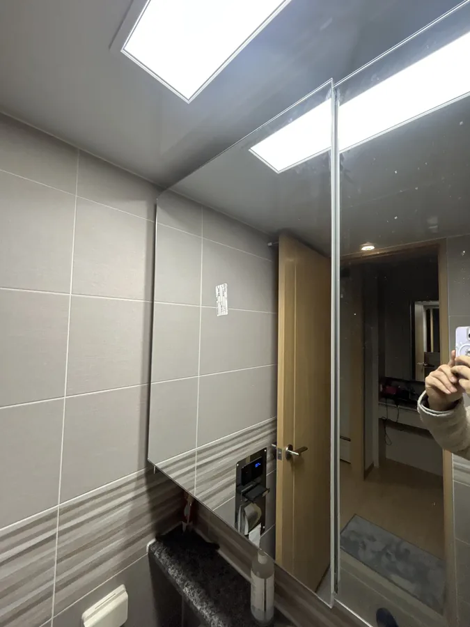 깨진 욕실 거울교체 후, 새 거울로 교체된 세면대 벽면